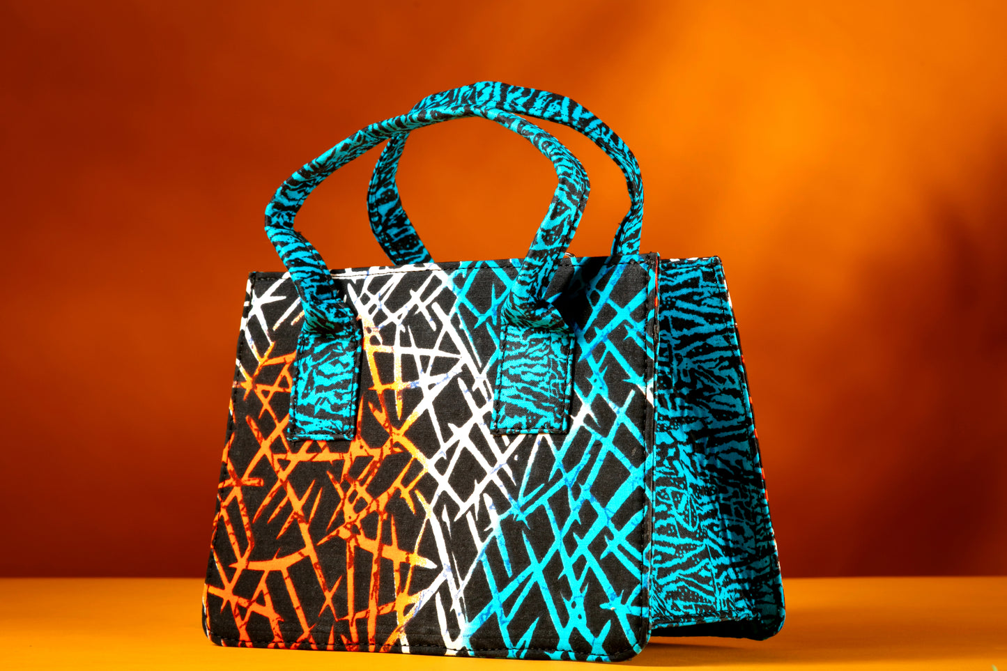 Side angle of the Gyil Bag highlighting the vibrant contrast between the front, side and the handles, handmade with African wax cotton.