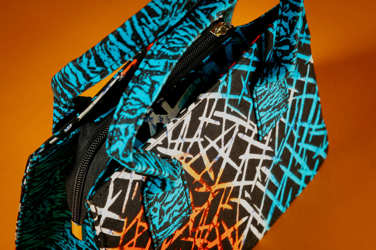 Close-up of the Gyil Bag showing detailed Ankara fabric, unique top handles in a different print, and the bag's sturdy, artistic silhouette.