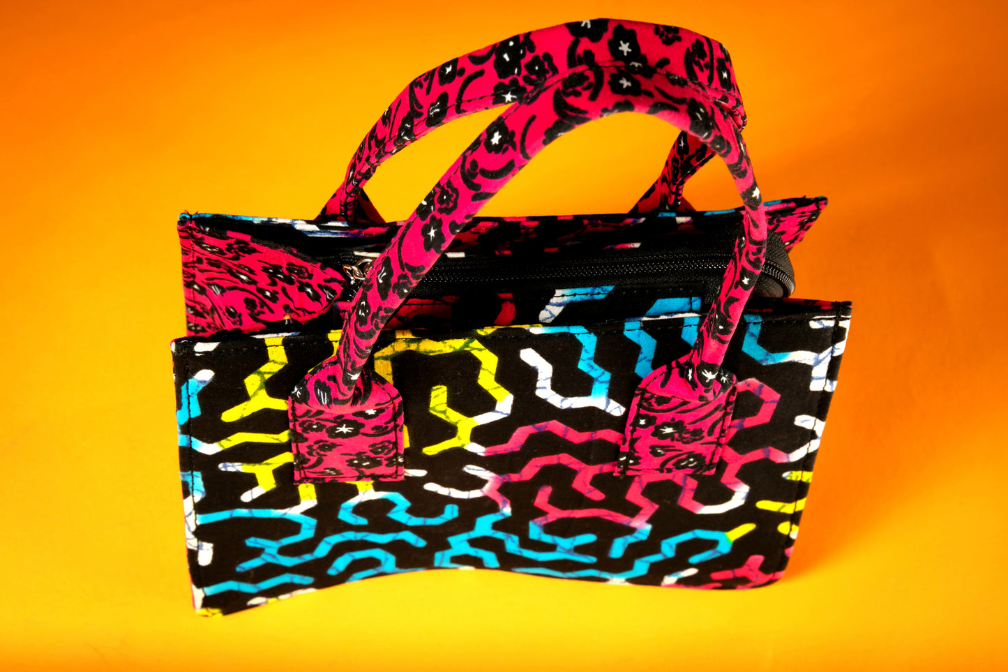 Close-up of the Ncegele Bag showing detailed Ankara fabric, unique top handles in a different print, and the bag's sturdy, artistic silhouette.