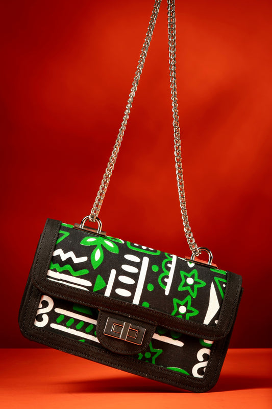 Axatse African print handbag with green and white Ankara fabric and black denim trim, featuring a silver chain strap and chrome twist-lock closure, handmade in Nigeria.