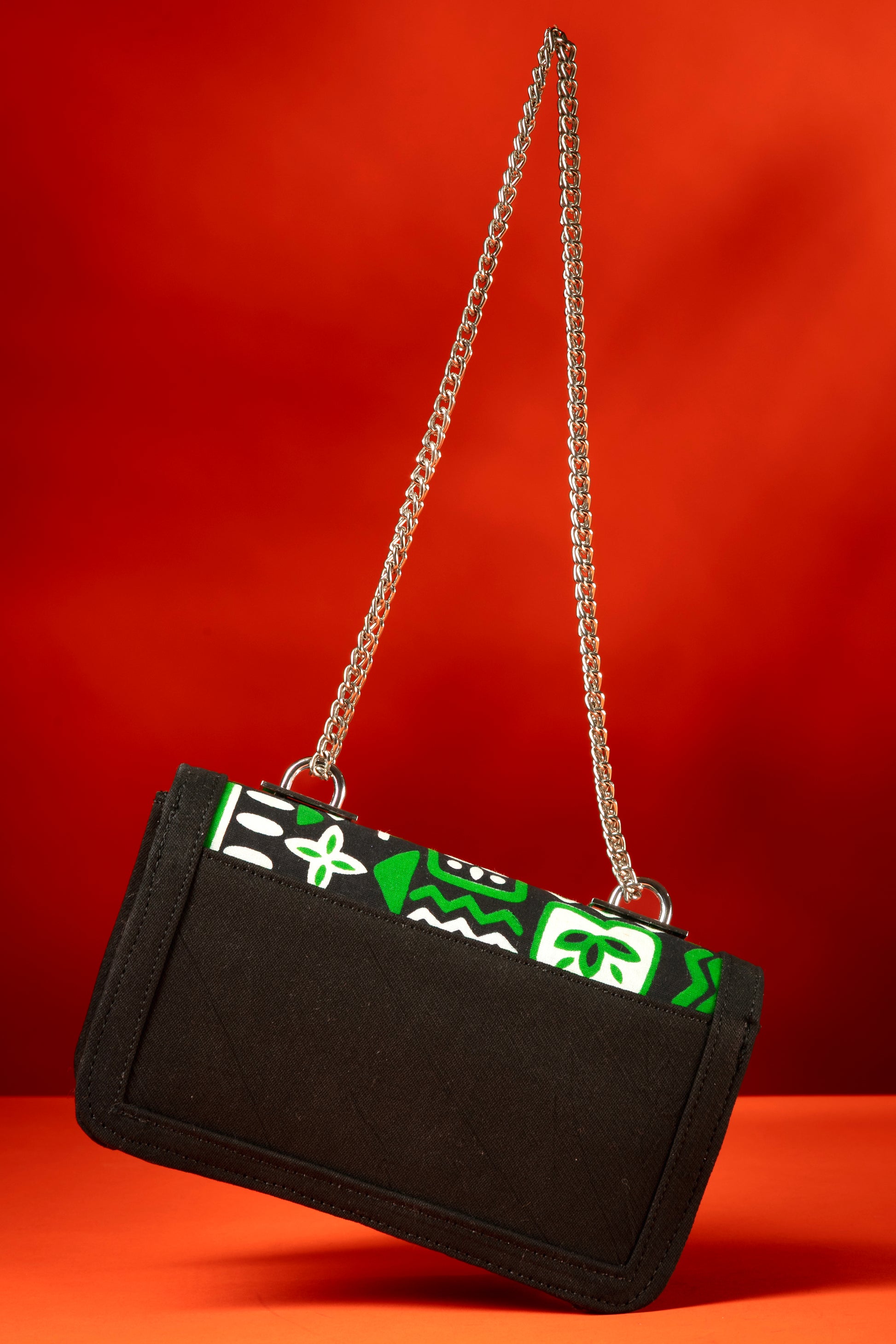 Back view of Axatse African print and denim bag with bold green, white, and black Ankara pattern, accented by a silver chain strap.