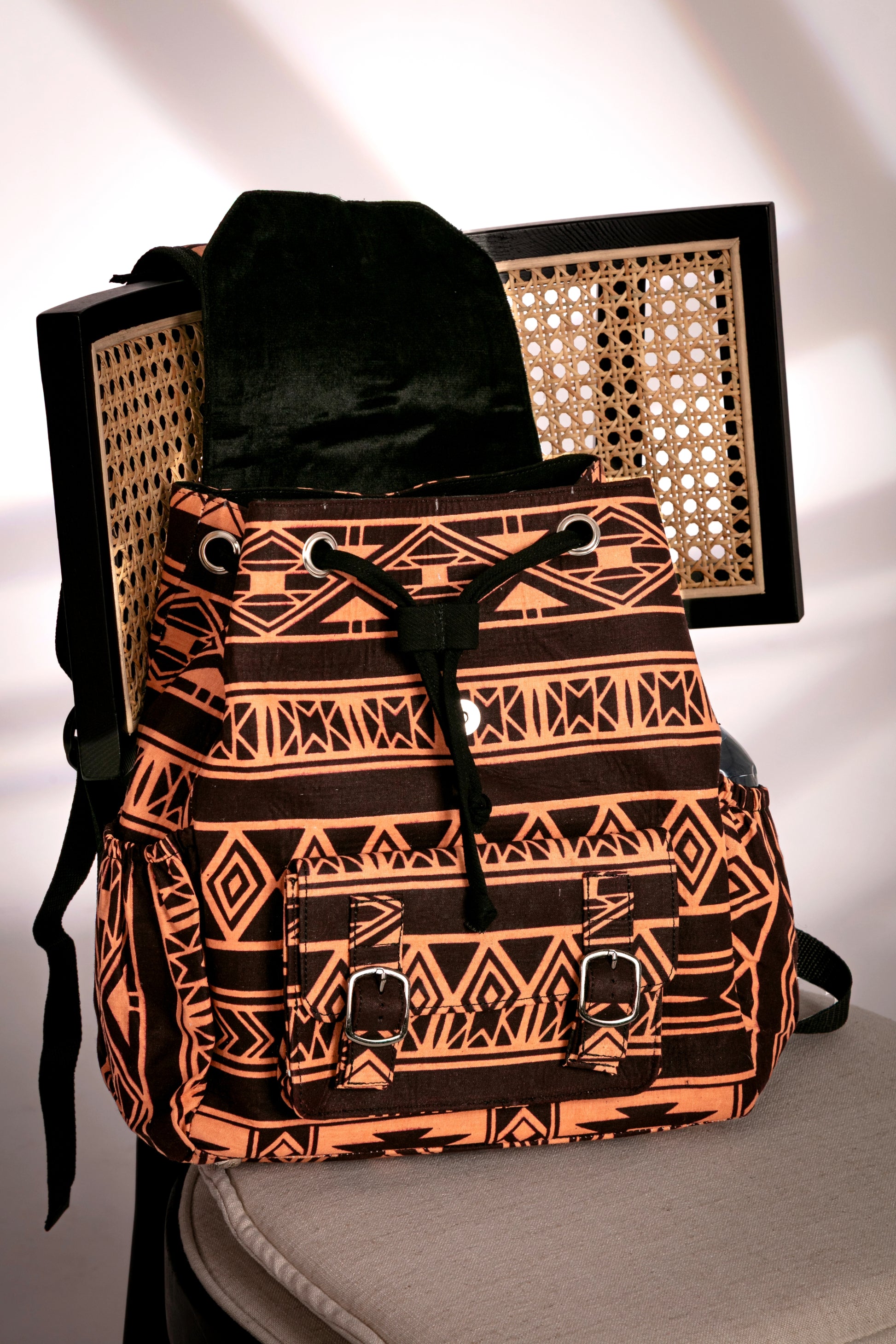 Front view of backpack with brown and nude tribal pattern with flap opened on a chair
