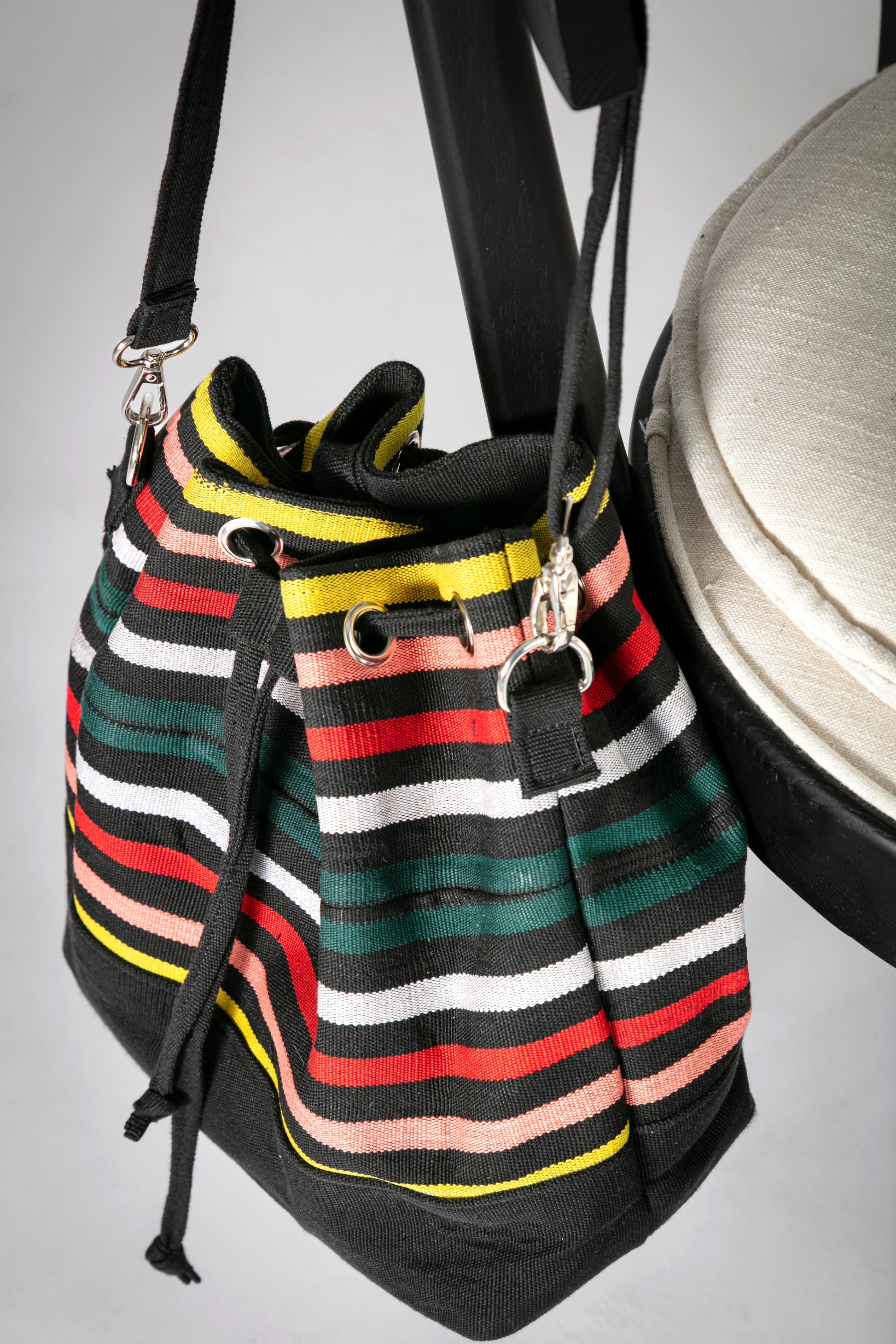 Multicolor striped bucket bag with a drawstring closure hanging on a chair