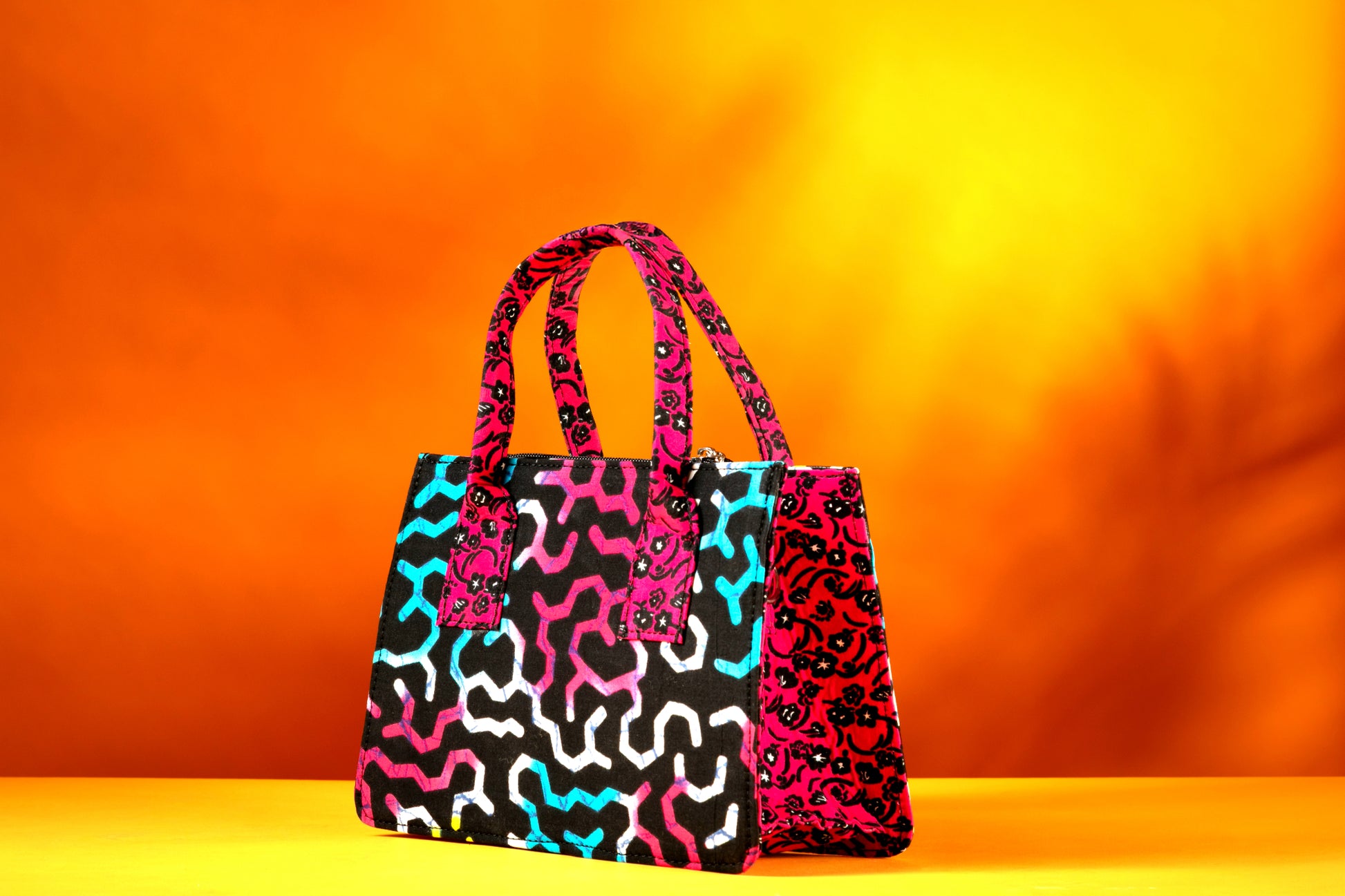 Side angle of the Ncegele Bag highlighting the vibrant contrast between the front, side and the handle, handmade with African wax cotton.
