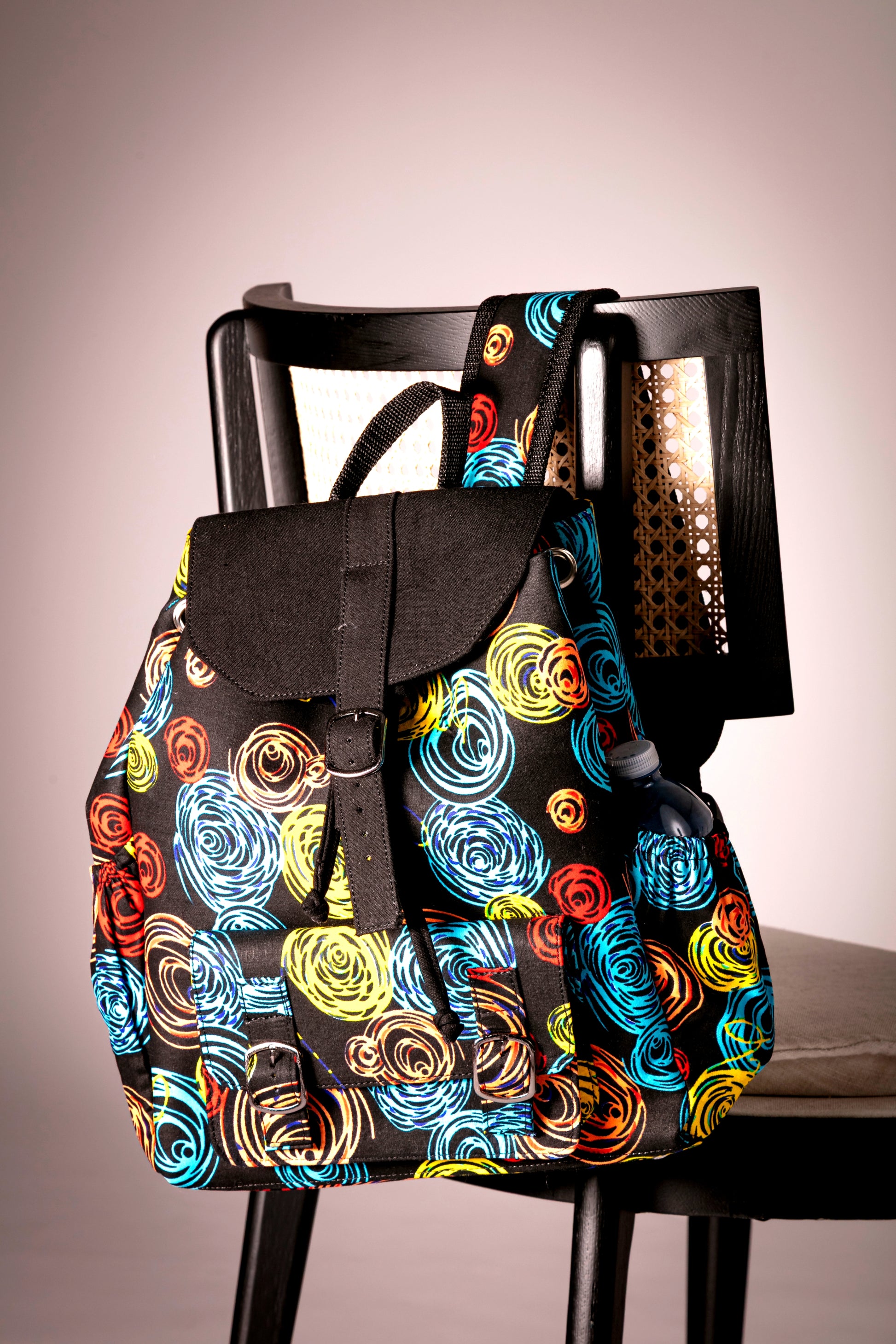 Front view of backpack with colorful circular pattern hanging on a chair 