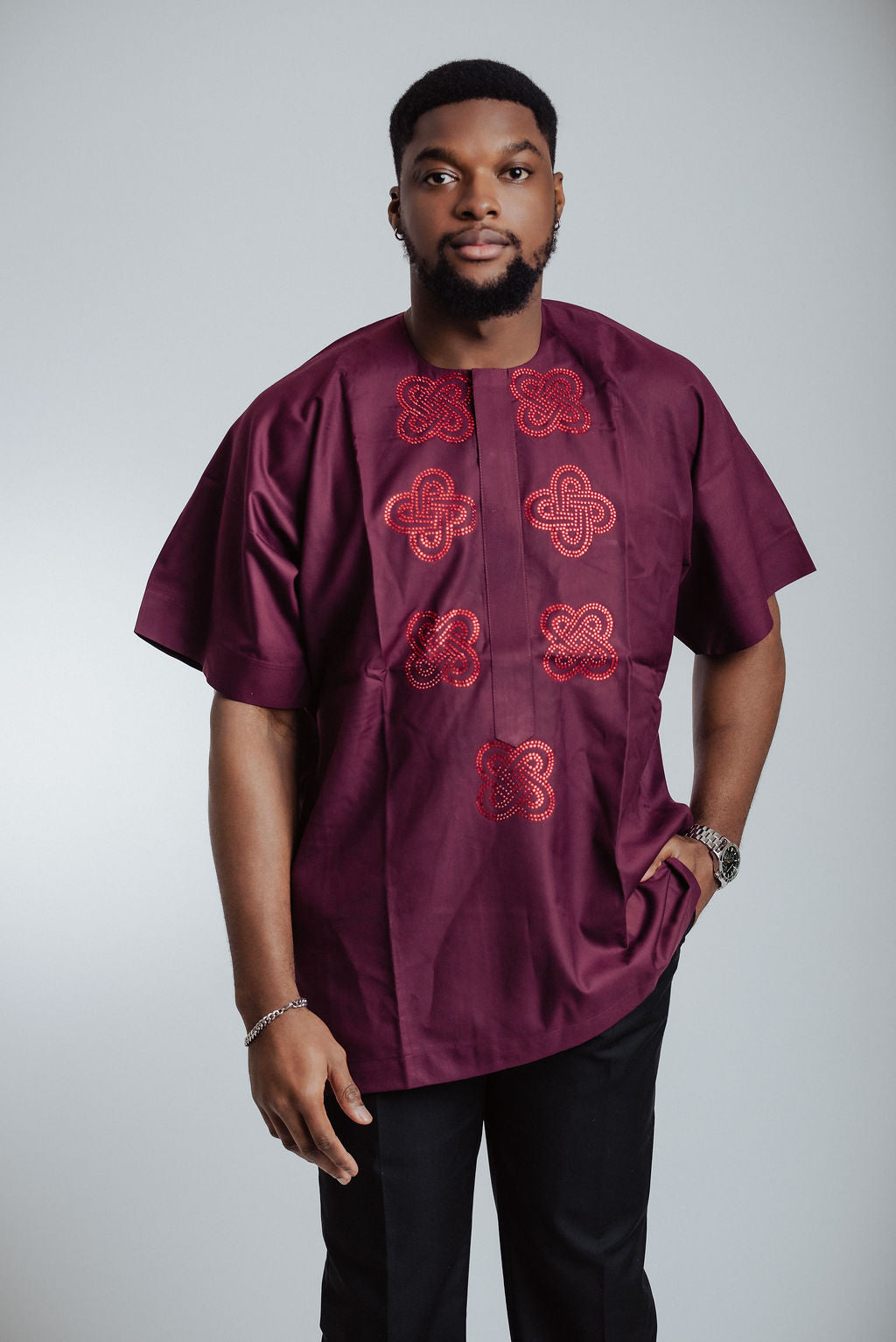 Man wearing a maroon shirt with red patterns on a white background